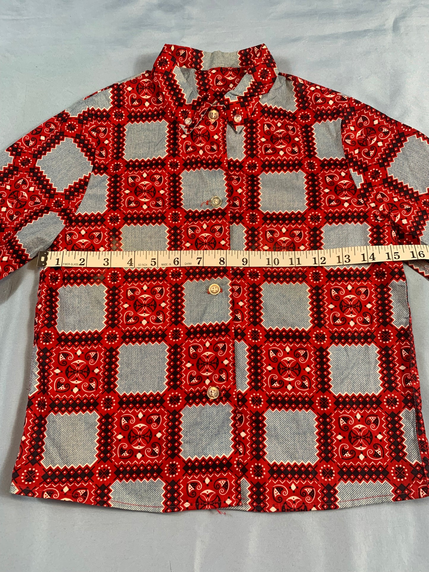 Red and black patterned fabric with a measuring tape on a white background