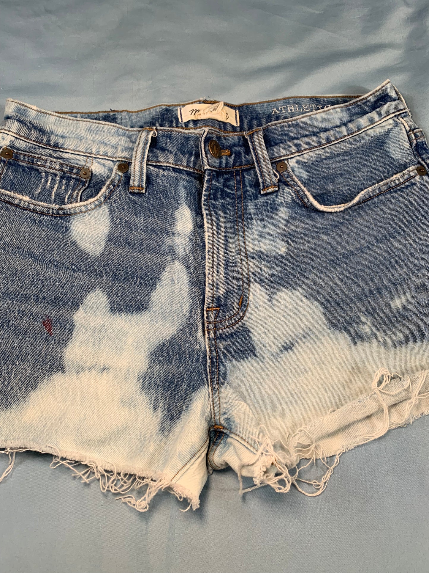 Distressed denim shorts with frayed edges on a gray background