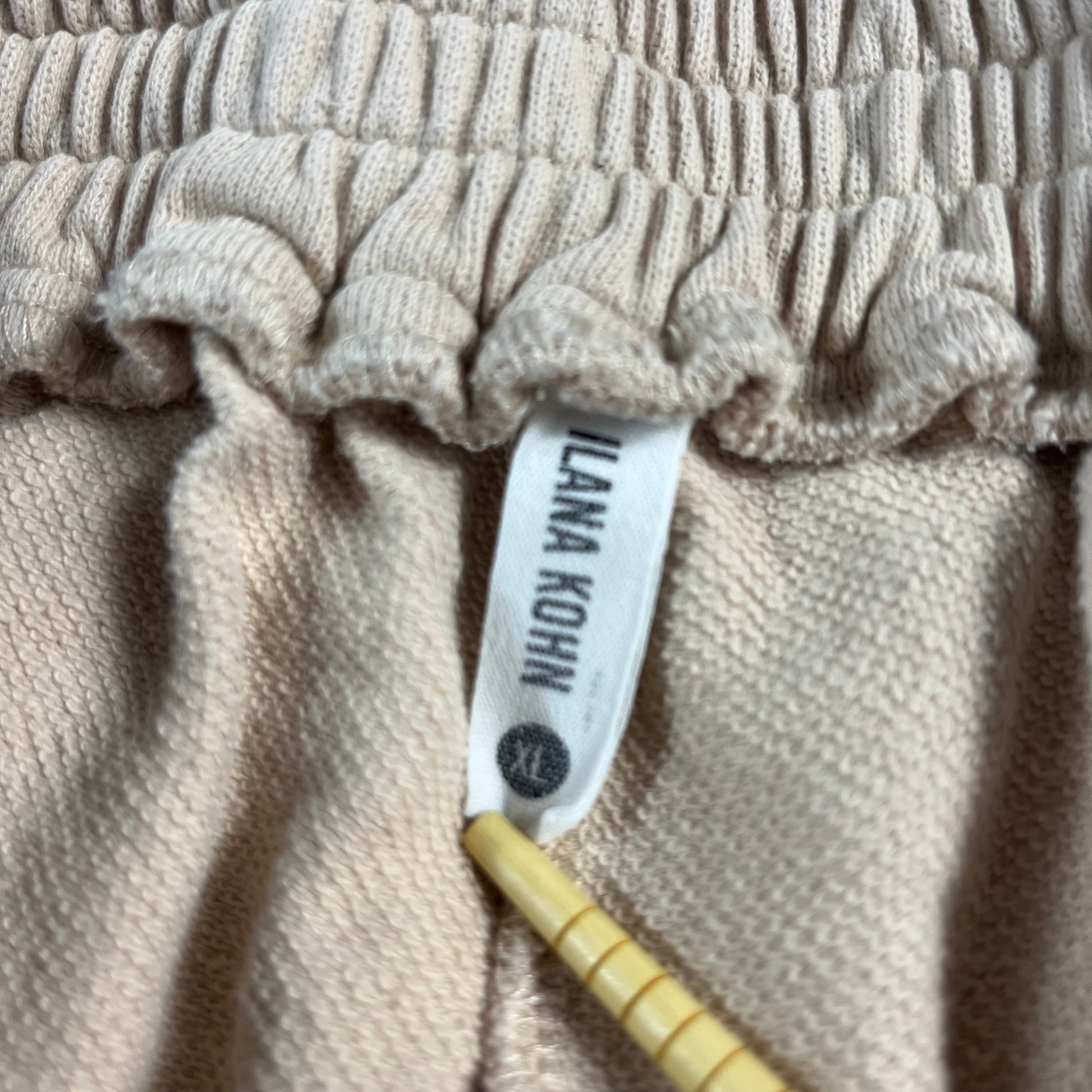 Close-up of beige textured fabric with a label on a beige background