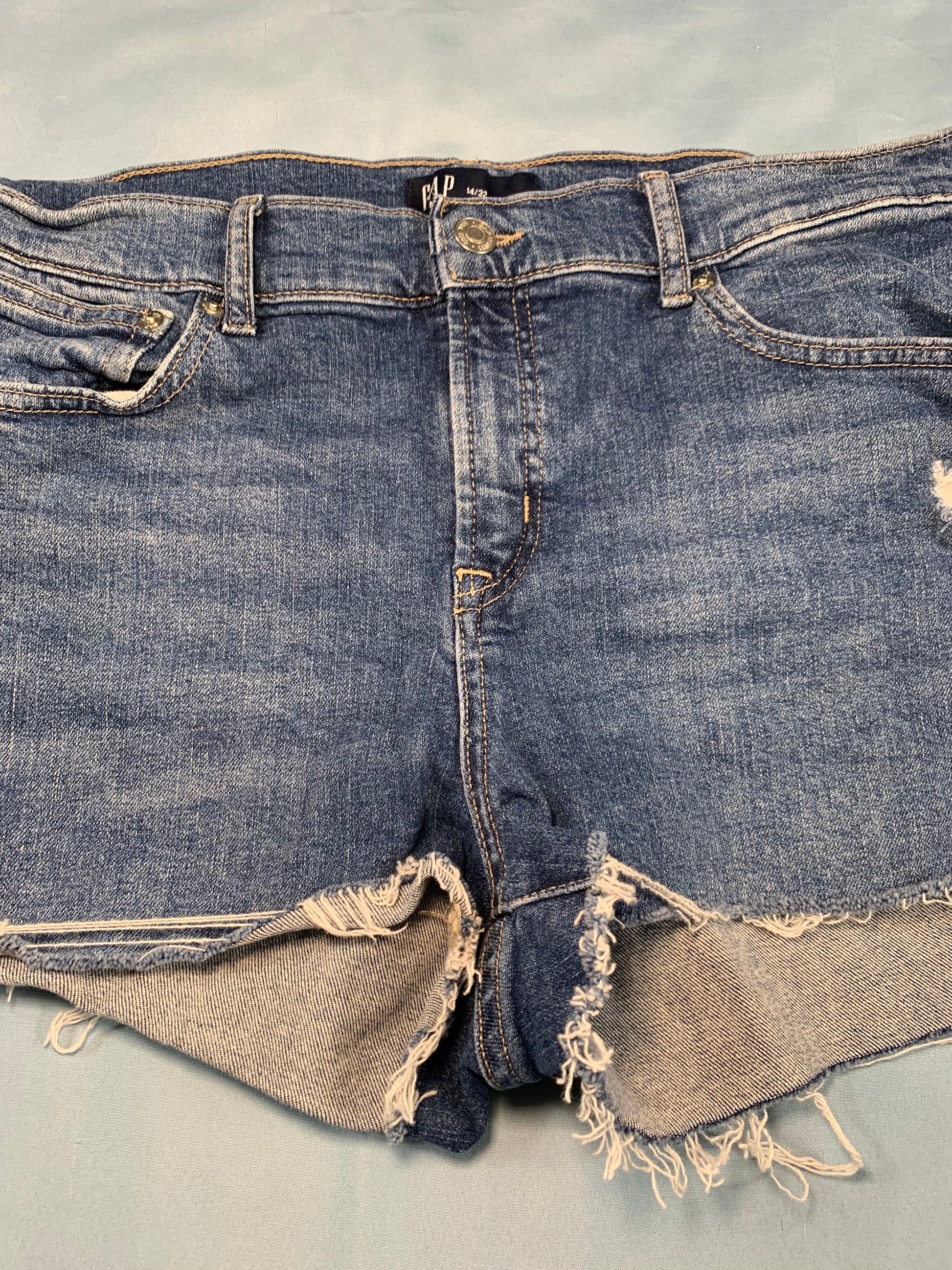 Denim overalls with frayed edges on a gray background