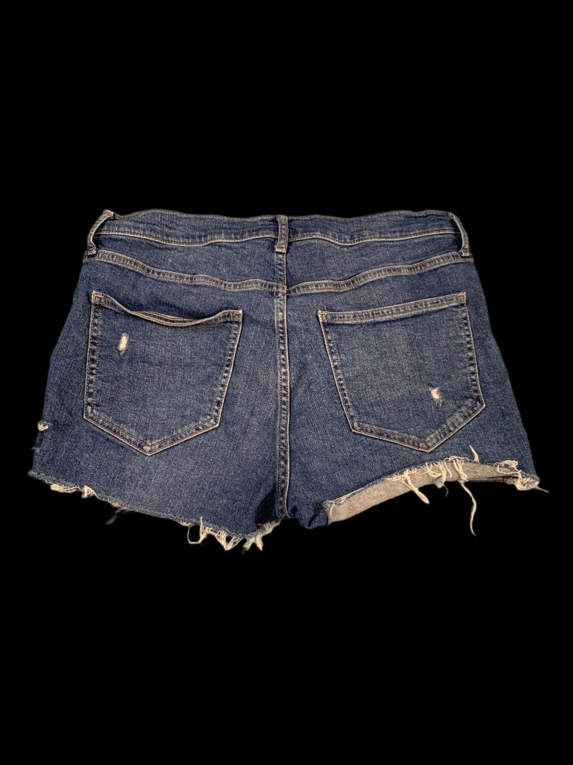 Folded pair of blue jeans with frayed edges on a light gray background